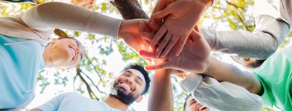 View from below of students connecting hands in a circle