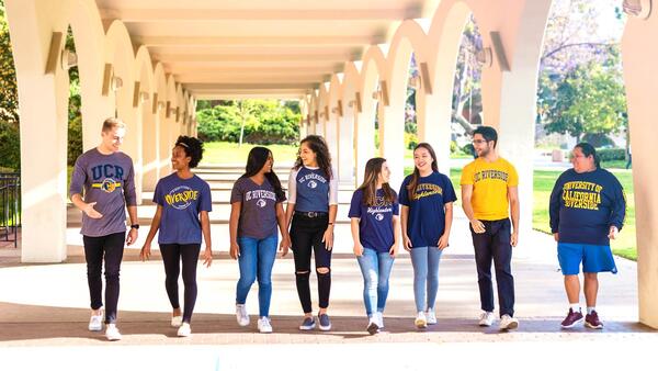 UCR Students walking under the Rivera Library arches.