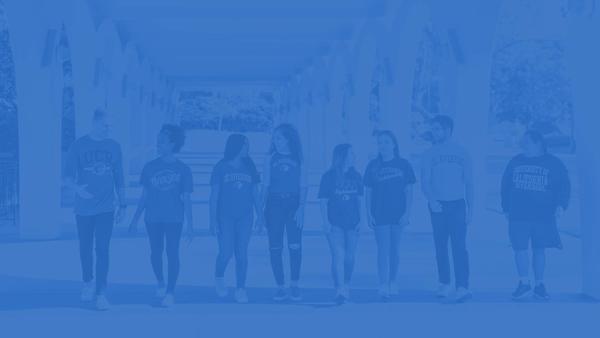 UCR Students walking under the Rivera Library arches.