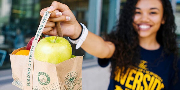 UCR student holds up bag of free fruit.
