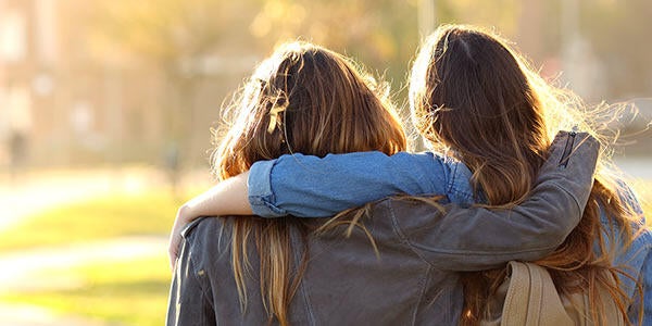 Student comforts friend while walking through campus.