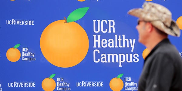 A participant walks in front of UCR's Healthy Campus Initiative signage.